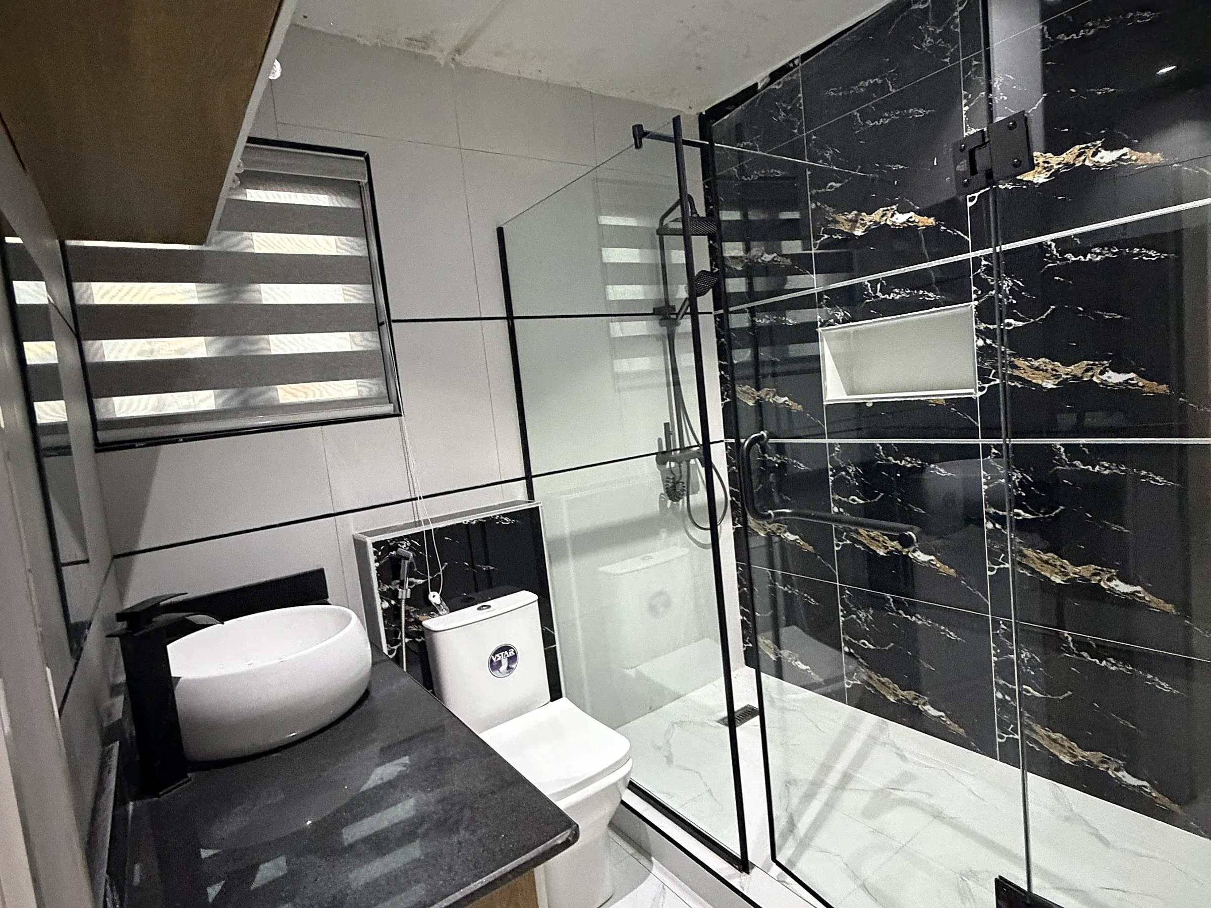 Primary en-suite bathroom with glass shower enclosure and black marble-effect feature wall