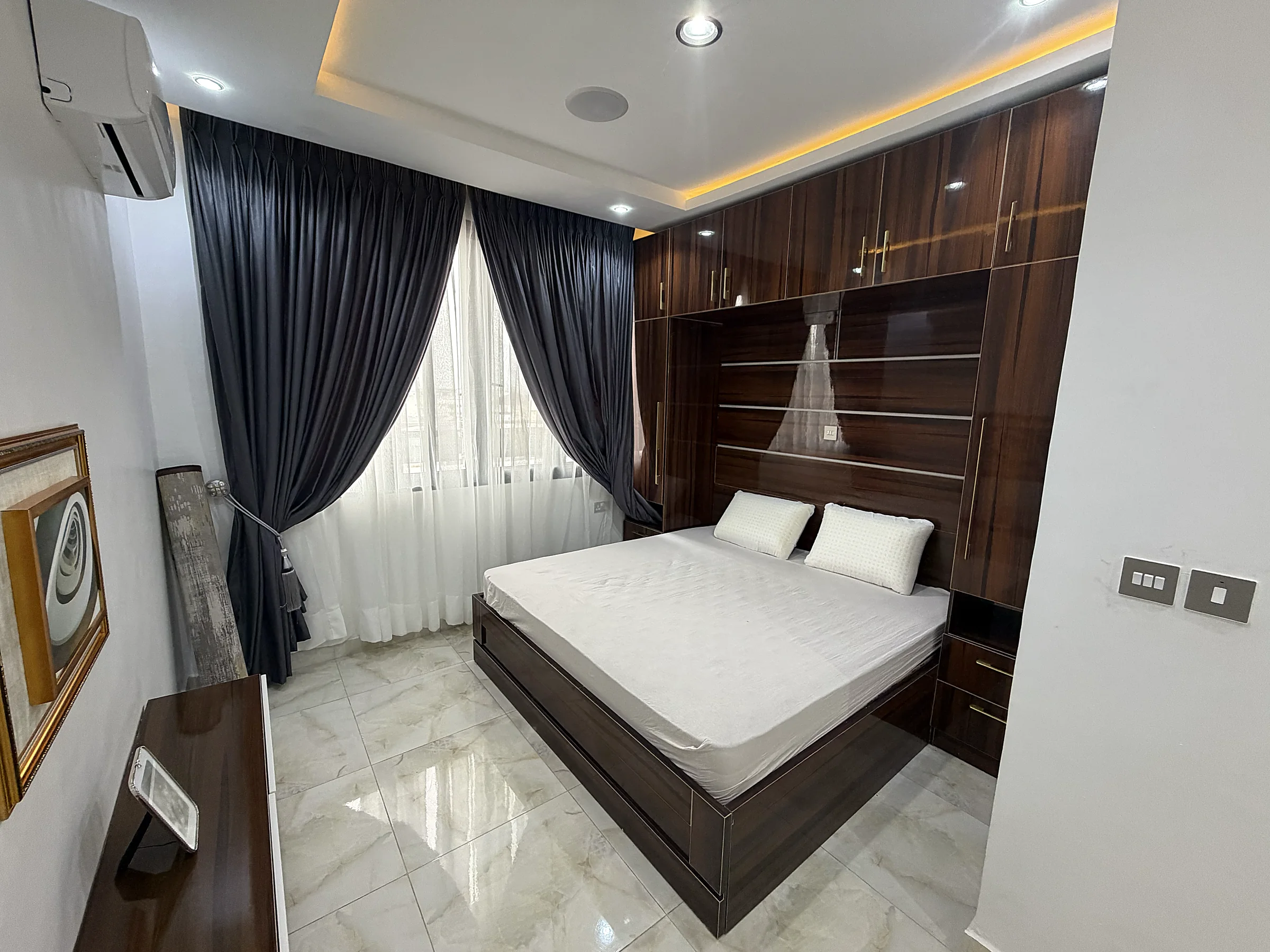 Third bedroom with dark timber fitted storage and full-height curtains