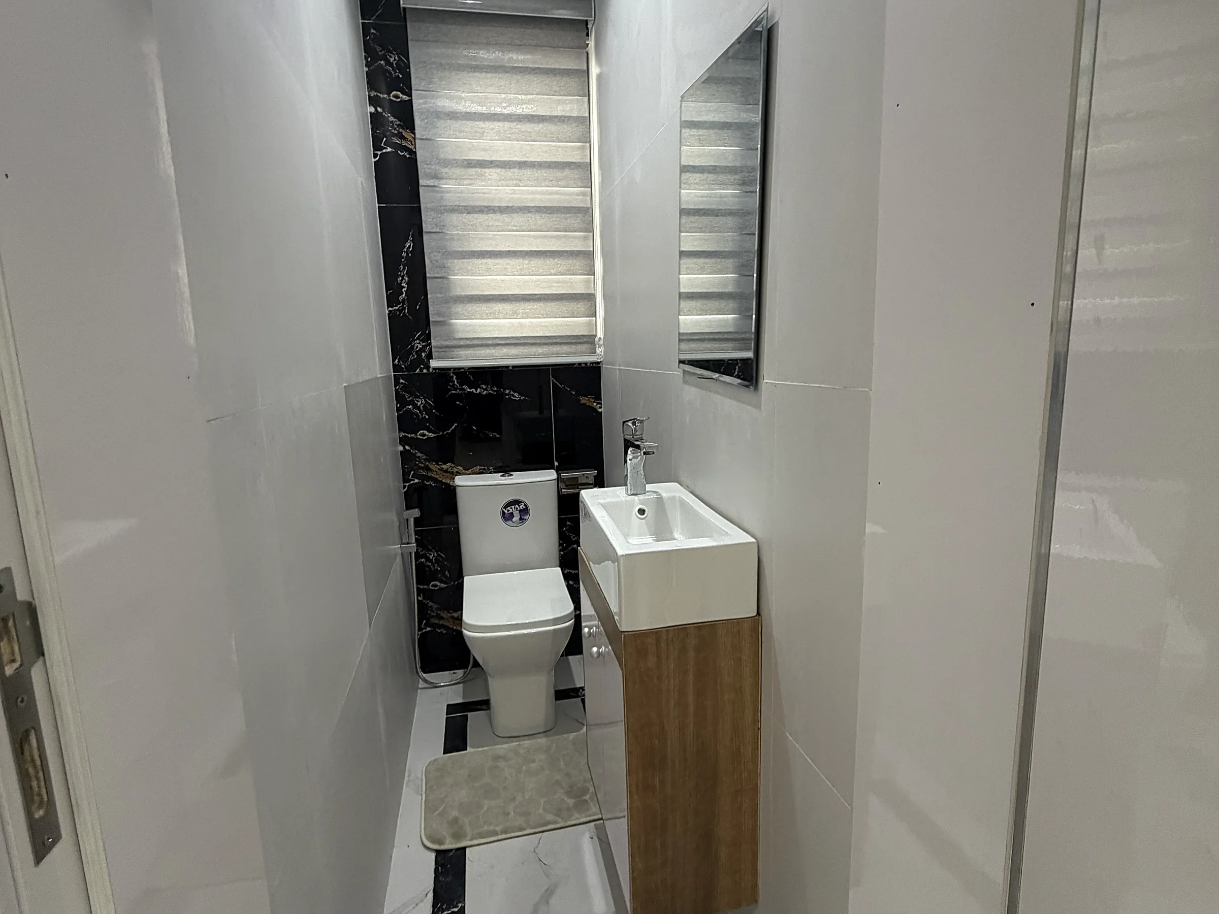 Guest washroom with a fitted vanity, mirror and patterned privacy blind