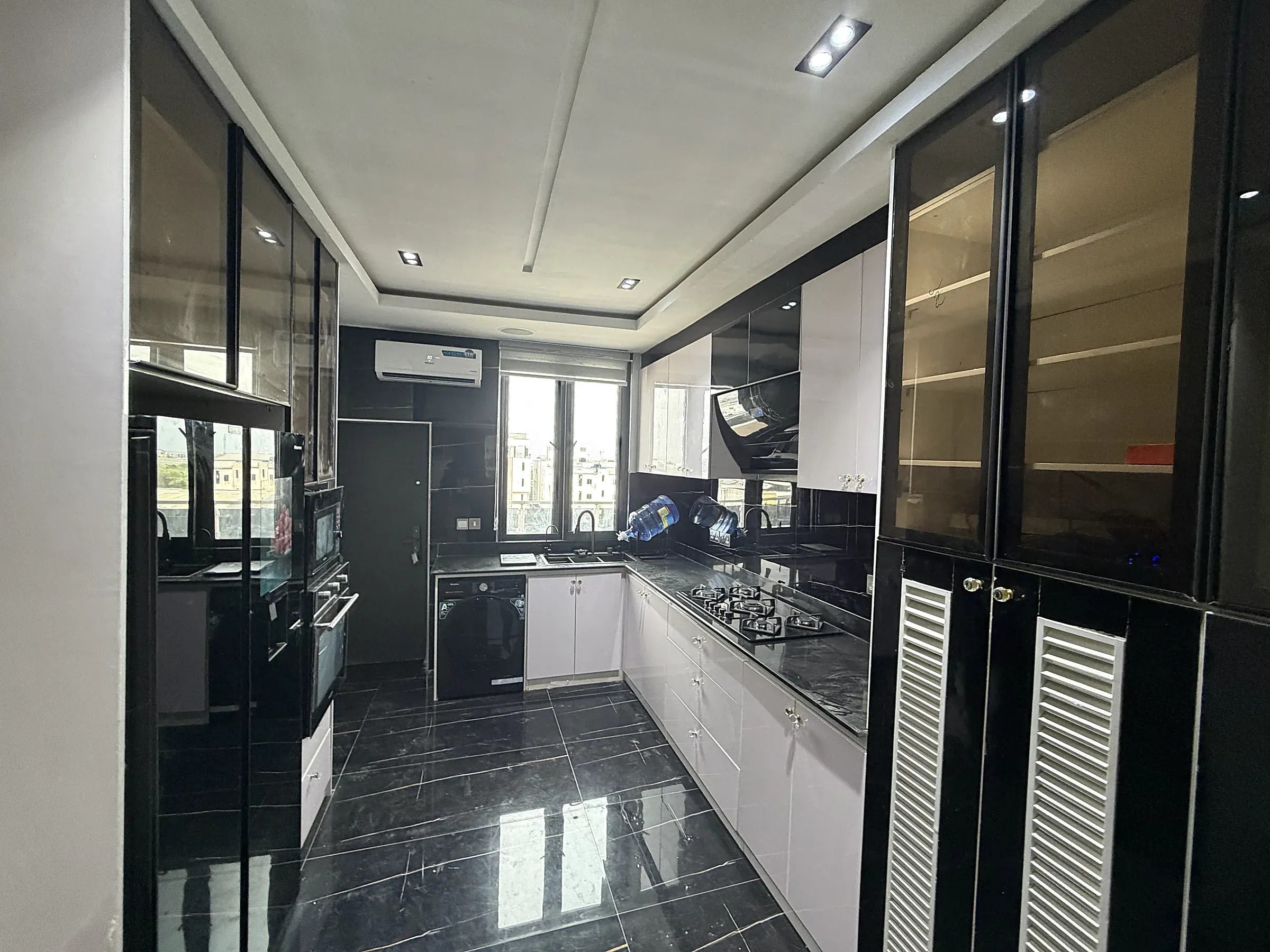Full black and white kitchen with fitted cabinetry, cooking area and city-facing windows