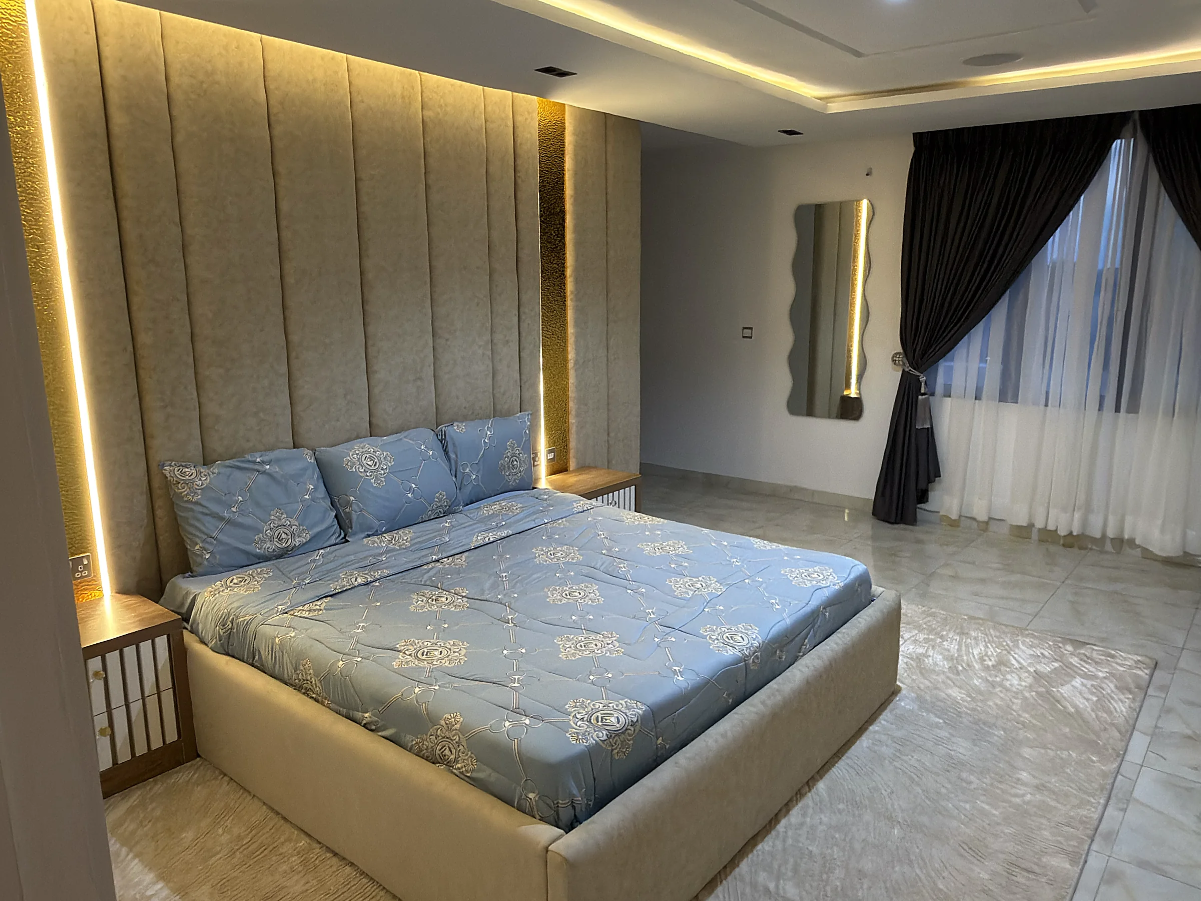 Primary bedroom with a padded feature wall and warm integrated lighting