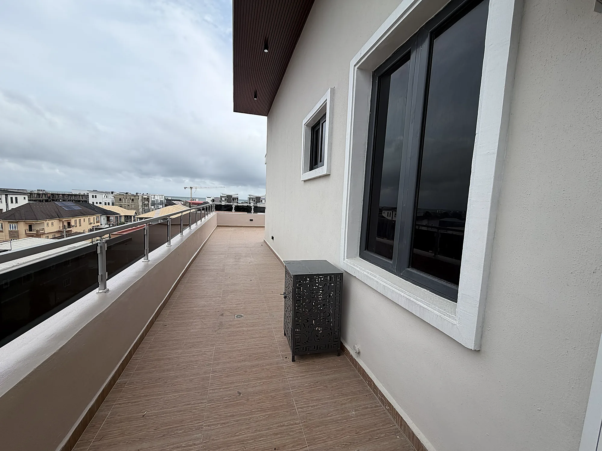 The upper open-air terrace with a glass balustrade and a view across Ilasan toward the coast